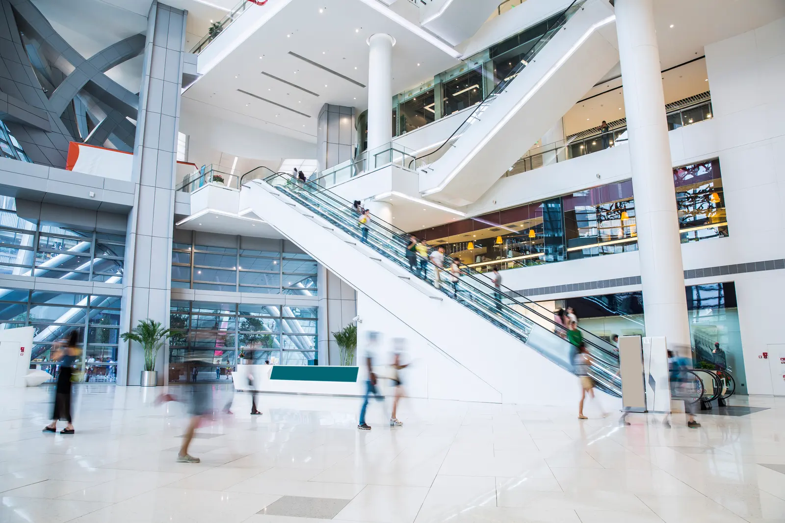 Shoppers on the escalators of a bright retail atrium